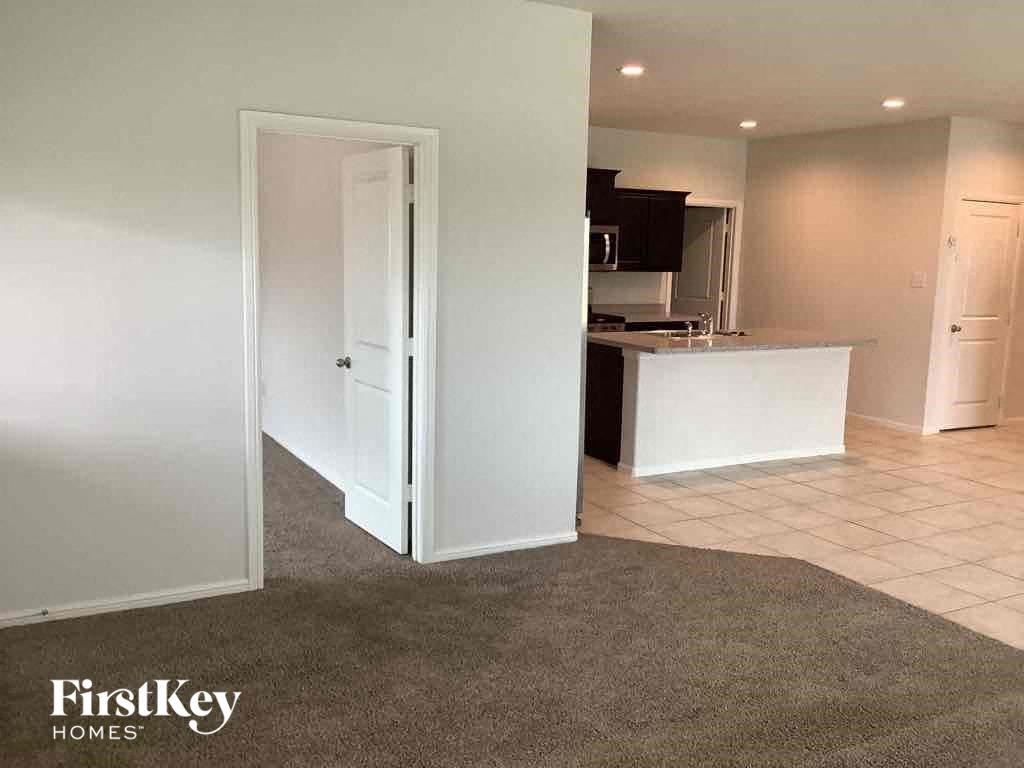 an empty kitchen with an open door to the living room