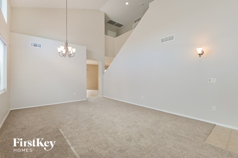 A spacious room with a carpeted floor and a chandelier hanging from the ceiling.