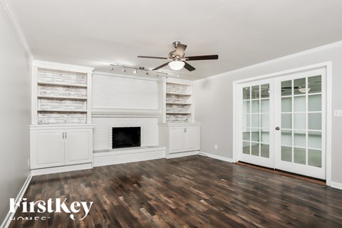 A spacious living room with wood flooring and a fireplace.
