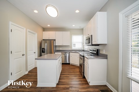 A kitchen with white cabinets and a wooden floor.
