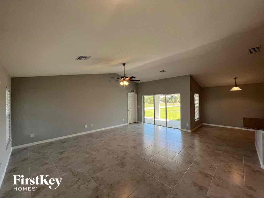 A spacious room with a fan and a sliding glass door leading to a grassy area.