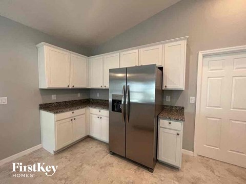 A kitchen with a stainless steel refrigerator and white cabinets.