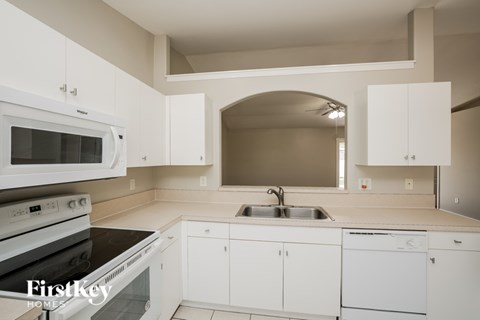 A kitchen with white appliances and cabinets.