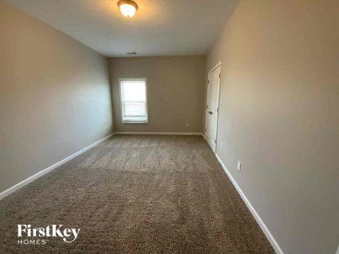 A carpeted room with a window and a door.