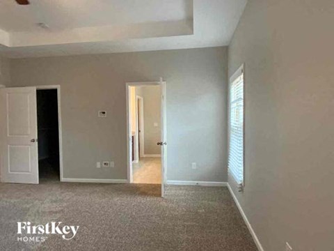 A room with a carpeted floor and two doors, one of which is open.