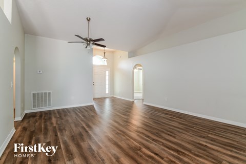a living room with white walls and wood floors and a ceiling fan