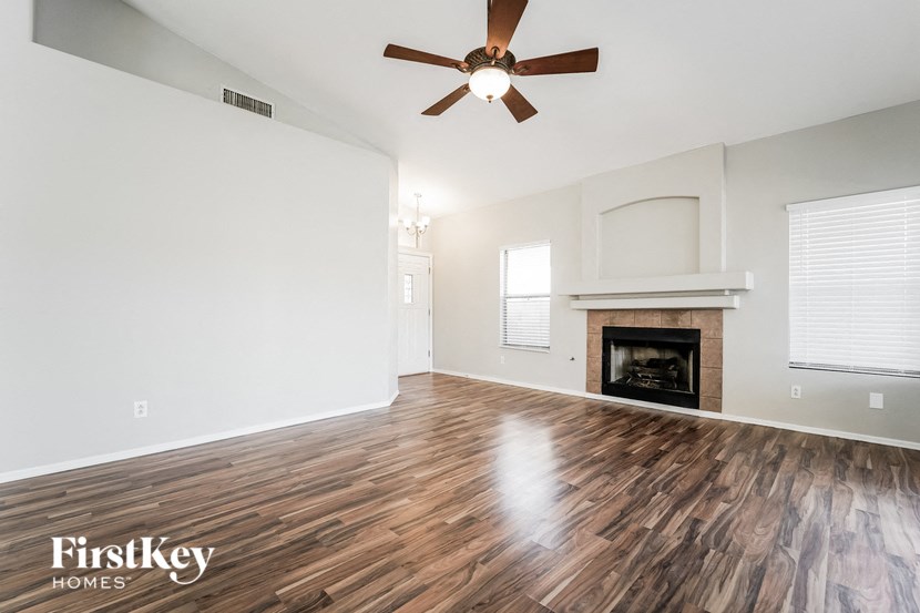 A spacious room with a fireplace and a ceiling fan.