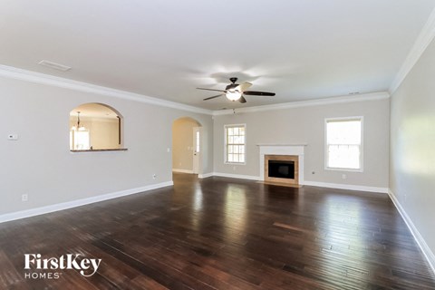 A spacious room with wood flooring and a ceiling fan.