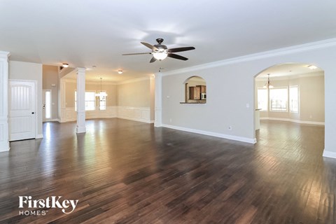 A spacious room with wooden floors and a ceiling fan.