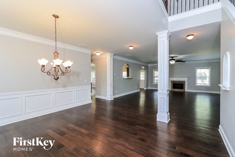A large, empty room with wooden floors and a chandelier.