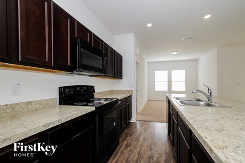 A kitchen with dark wood cabinets and a granite countertop.