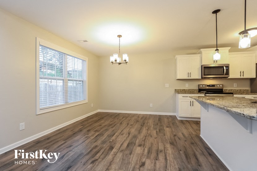 A kitchen with a wooden floor and a window with blinds.