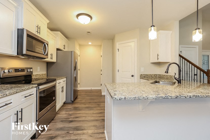 A kitchen with a granite countertop and a stainless steel refrigerator.
