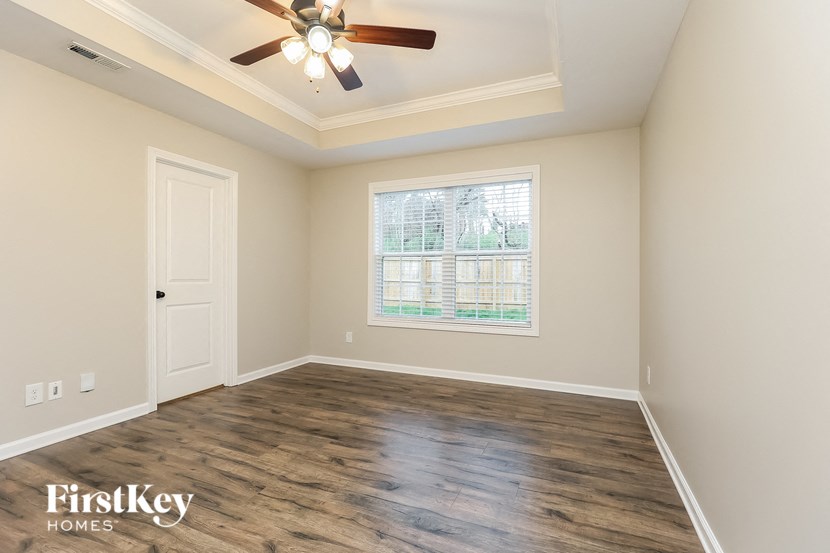 A room with a ceiling fan and wooden flooring.
