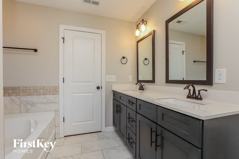 A bathroom with a white door, a white sink, and a mirror.