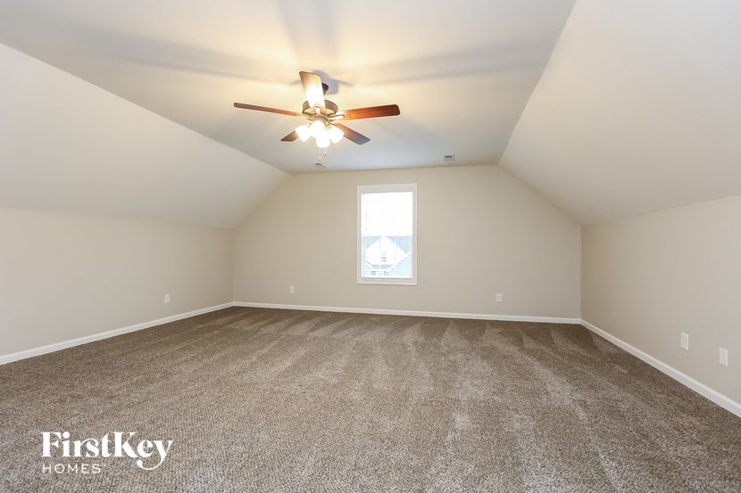 A spacious room with a ceiling fan and carpeted floor.
