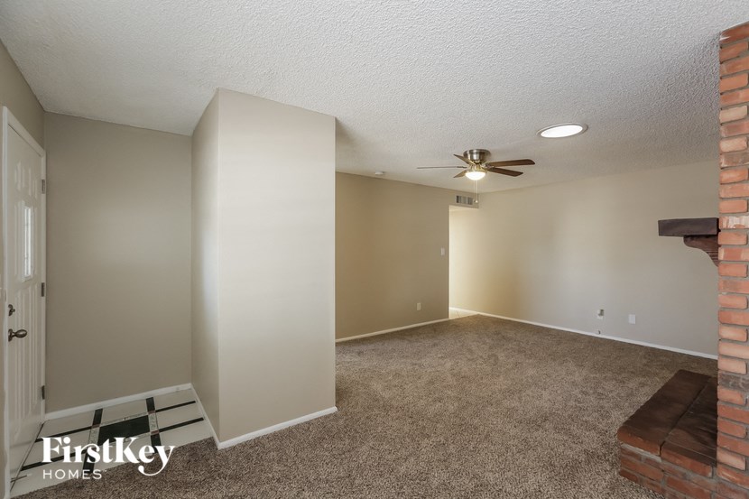 an empty living room with a ceiling fan and a brick fireplace