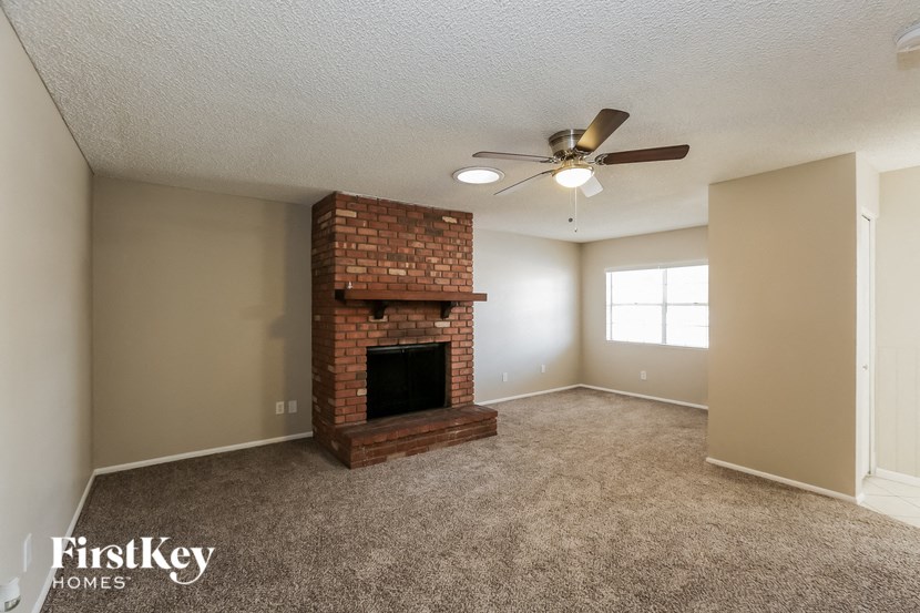 a living room with a brick fireplace and a ceiling fan