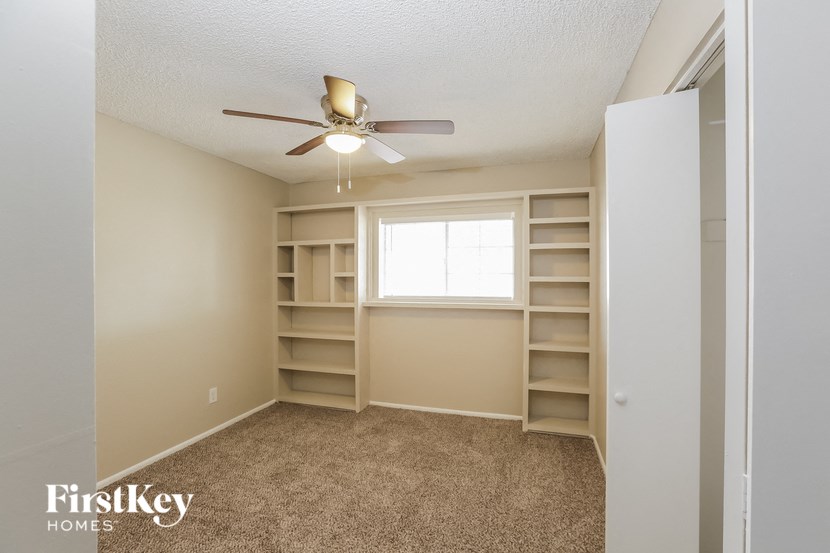 a room with shelves and a ceiling fan and a window
