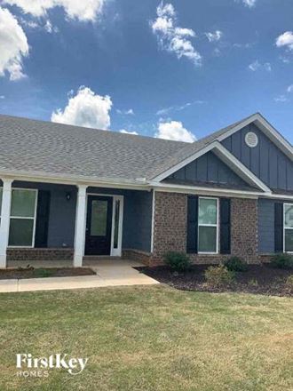 a brick house with a gray roof and a lawn