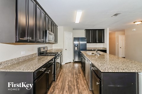 A kitchen with black cabinets and granite countertops.
