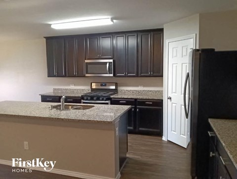 A kitchen with a black refrigerator and brown cabinets.