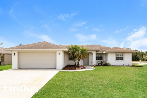 a white house with a lawn and a palm tree