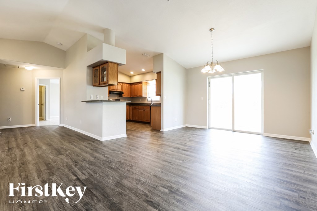 the living room and kitchen of an empty house with wood flooring