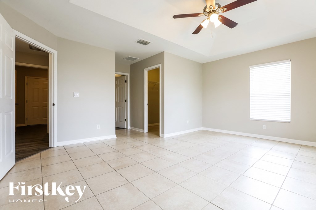 an empty living room with a ceiling fan and tiled floors