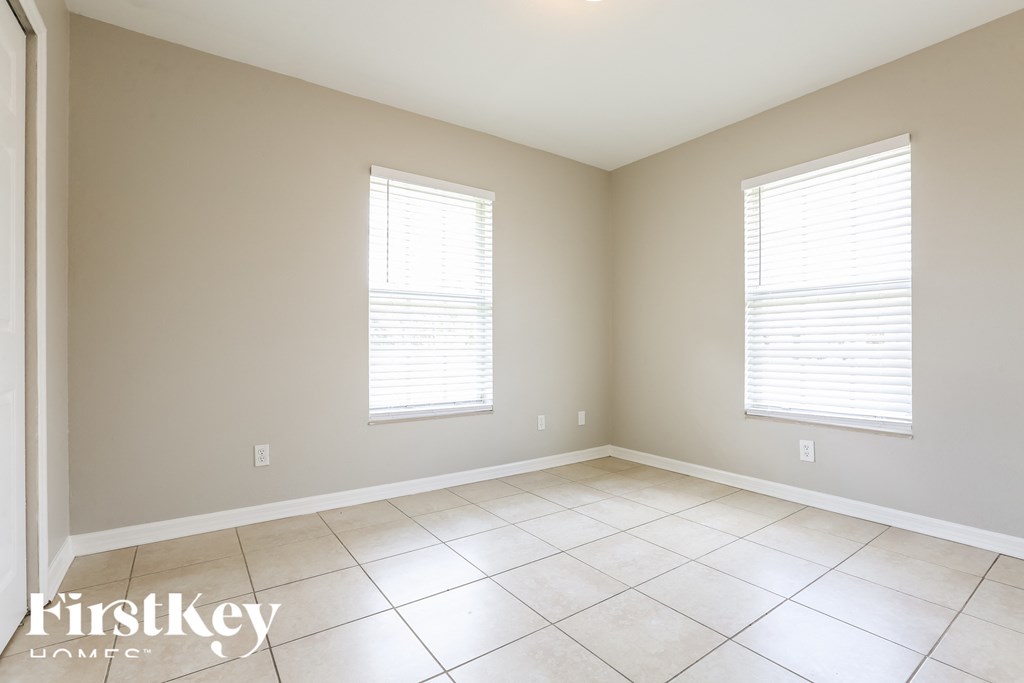 an empty room with two windows and a tiled floor
