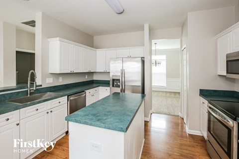 a kitchen with white cabinets and green counter tops