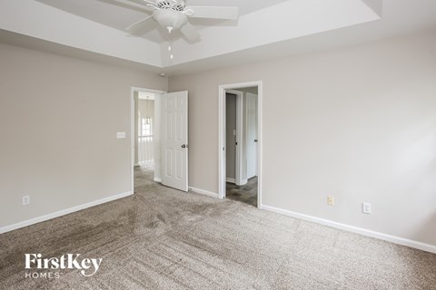 a spacious living room with carpet and a ceiling fan