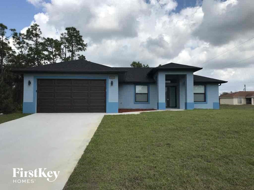 A blue house with a black garage door is for sale.