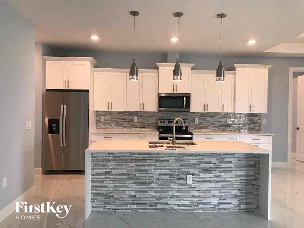 A kitchen with a stone counter top and a refrigerator.