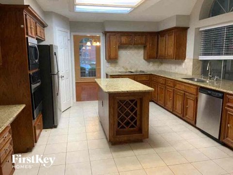 A kitchen with wooden cabinets and a black refrigerator.