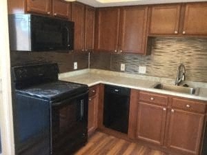 A kitchen with wooden cabinets and black appliances.