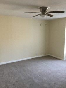 A room with a ceiling fan and carpeted floor.
