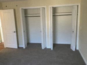 Three white closet doors are open in a room.
