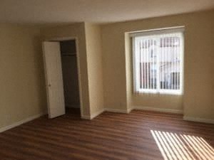 A room with a wooden floor and a window with blinds.