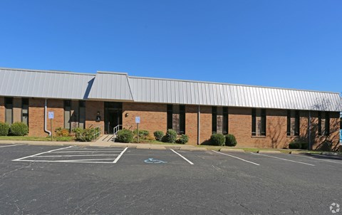an empty parking lot in front of a brick building with a metal roof