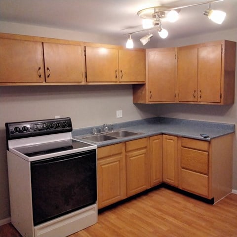 an empty kitchen with wooden cabinets and a stove and a sink