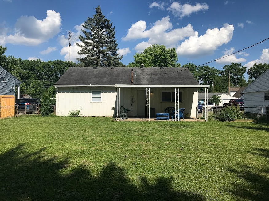 a small white house with a grassy yard and a tree