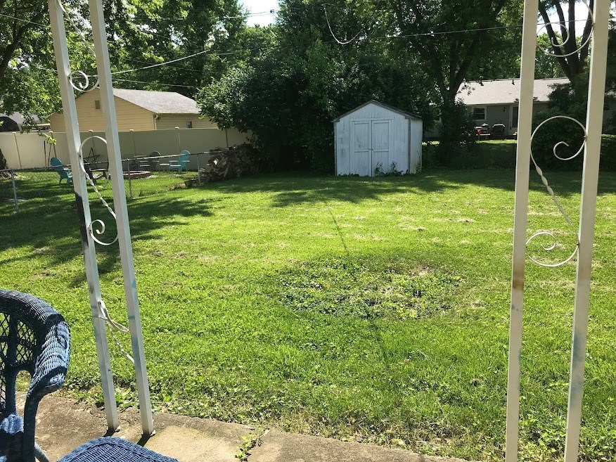 a backyard with a swing set and a shed in the yard