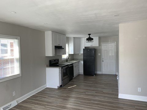 A kitchen with white cabinets and a black refrigerator.