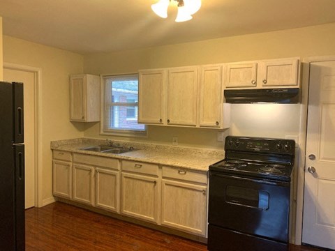 A kitchen with black appliances and white cabinets.