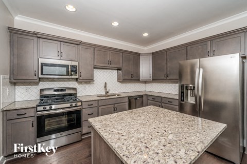 A kitchen with a granite countertop and stainless steel appliances.
