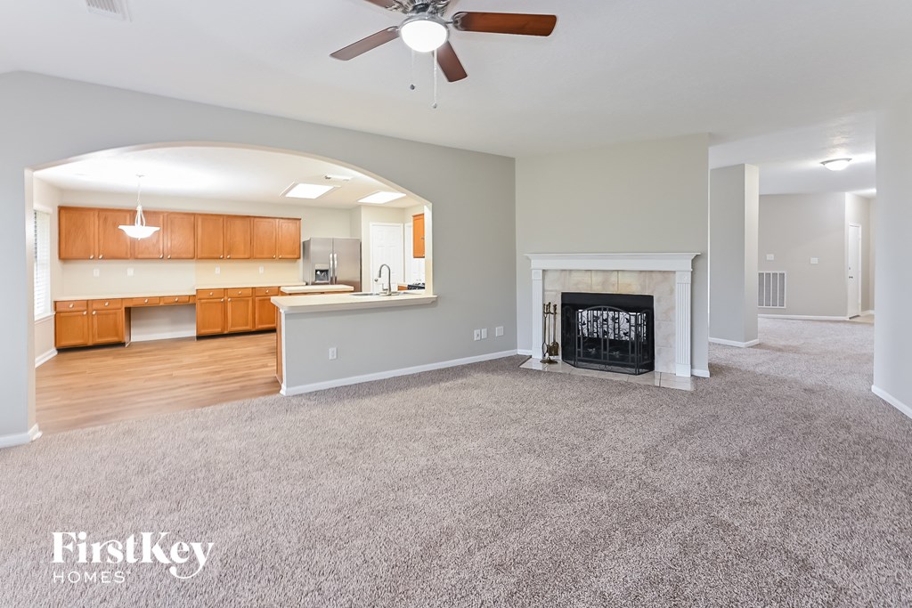 an empty living room with a fireplace and a kitchen