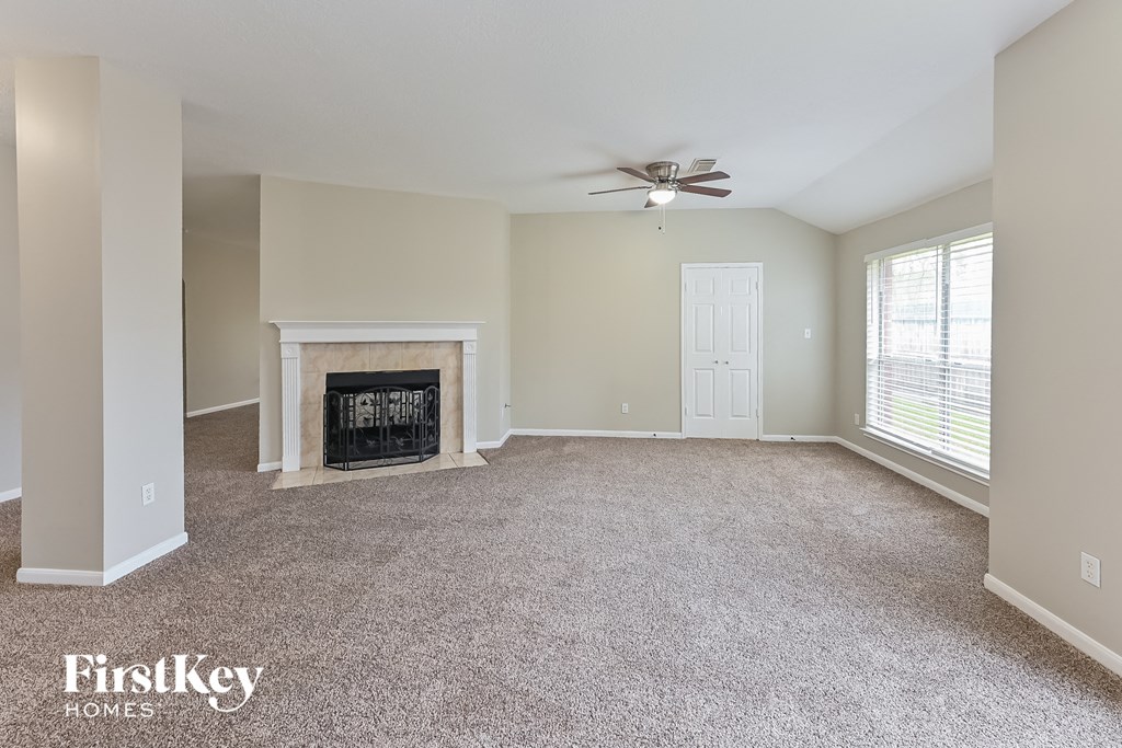 an empty living room with a fireplace and a ceiling fan