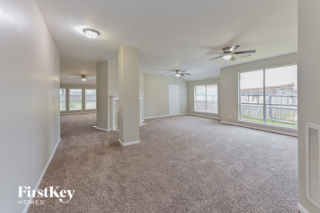 an empty living room with ceiling fans and a large window