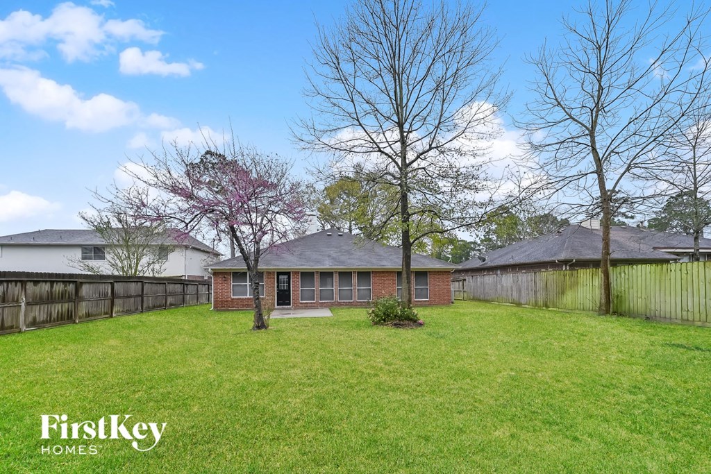 a small brick house with a yard and a fence